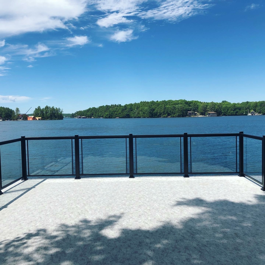 View of a lake through Glass railing on a newly resurfaced vinyl deck.